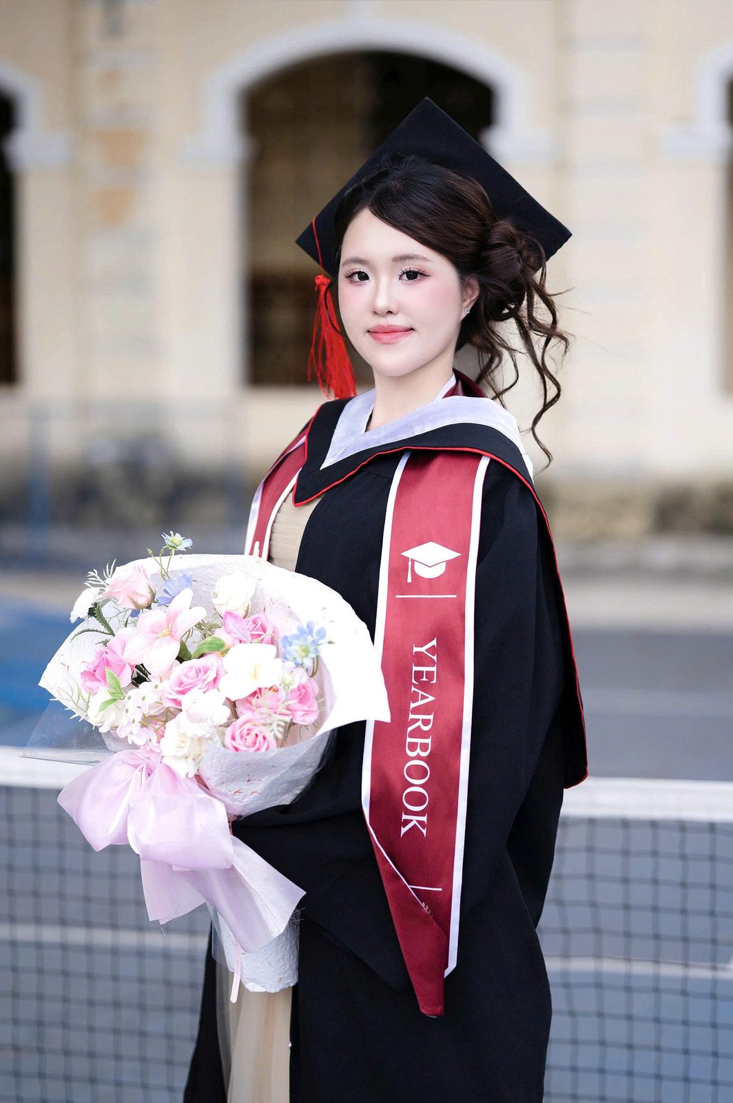 Tân cử nhân trong lễ phục, ôm bó hoa